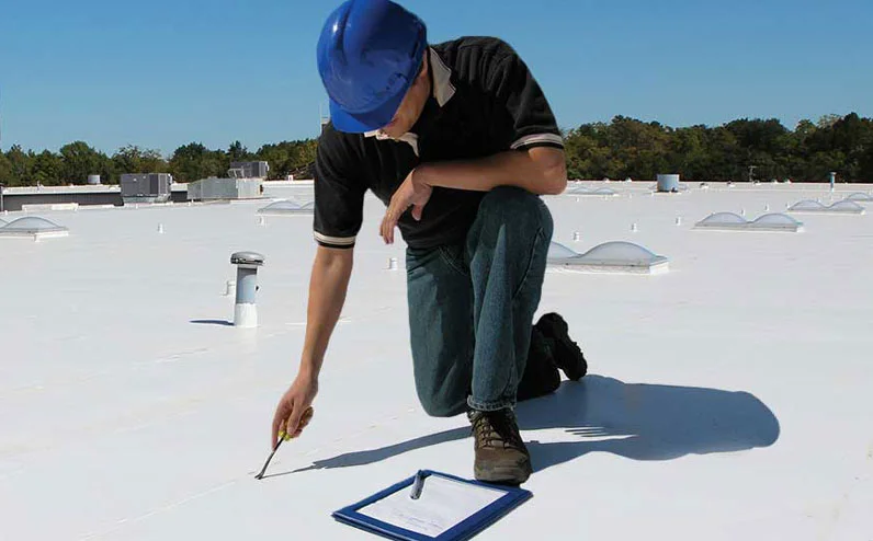 A roofing professional inspecting a flat commercial roof